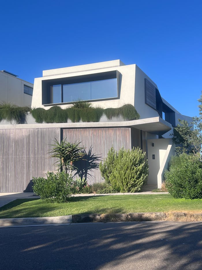 Modern home exterior with lush landscaping under clear blue skies.